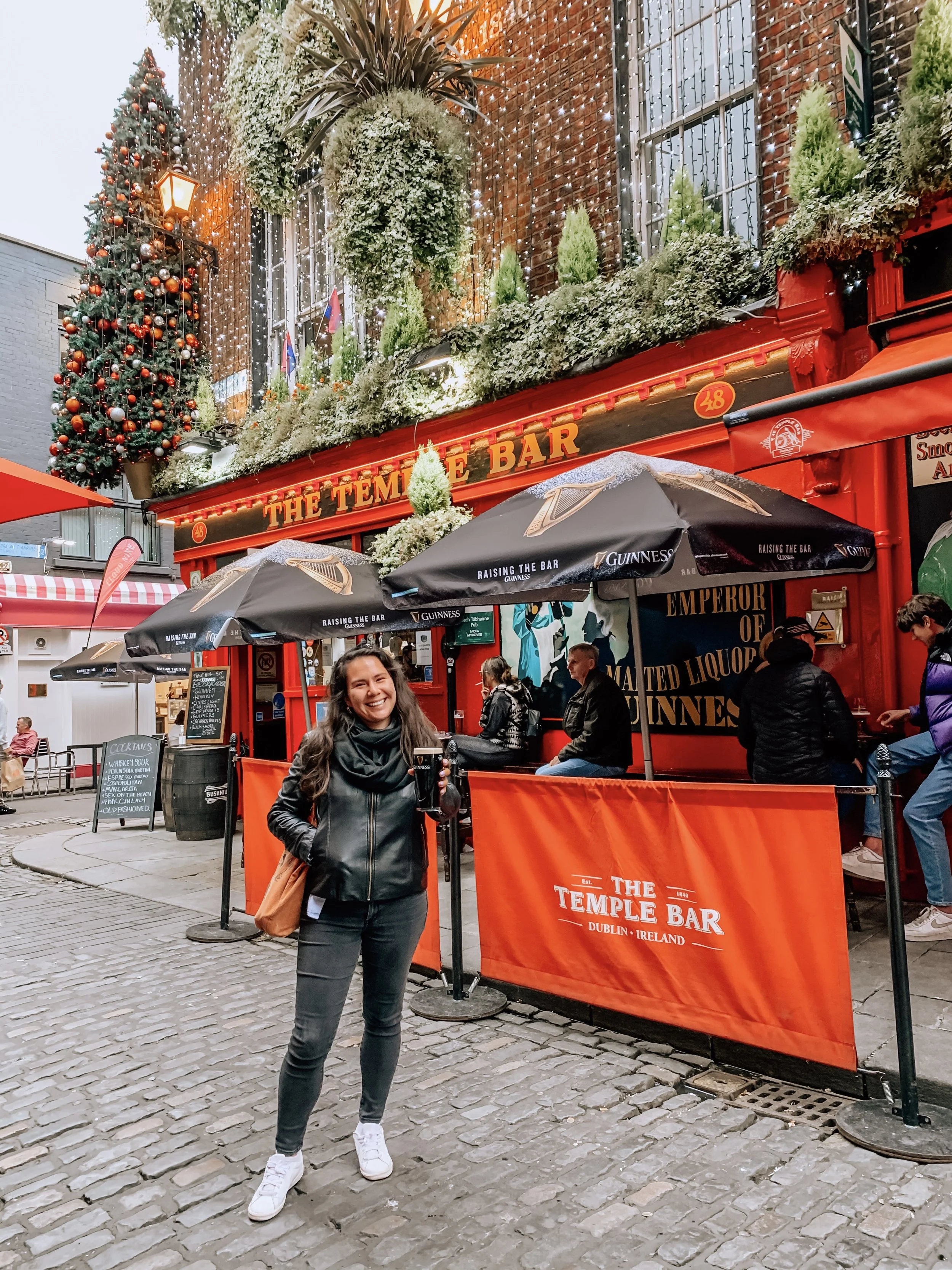 Flavia Cornejo, Latina Traveller, smiling with a beer in Dublin, Ireland.