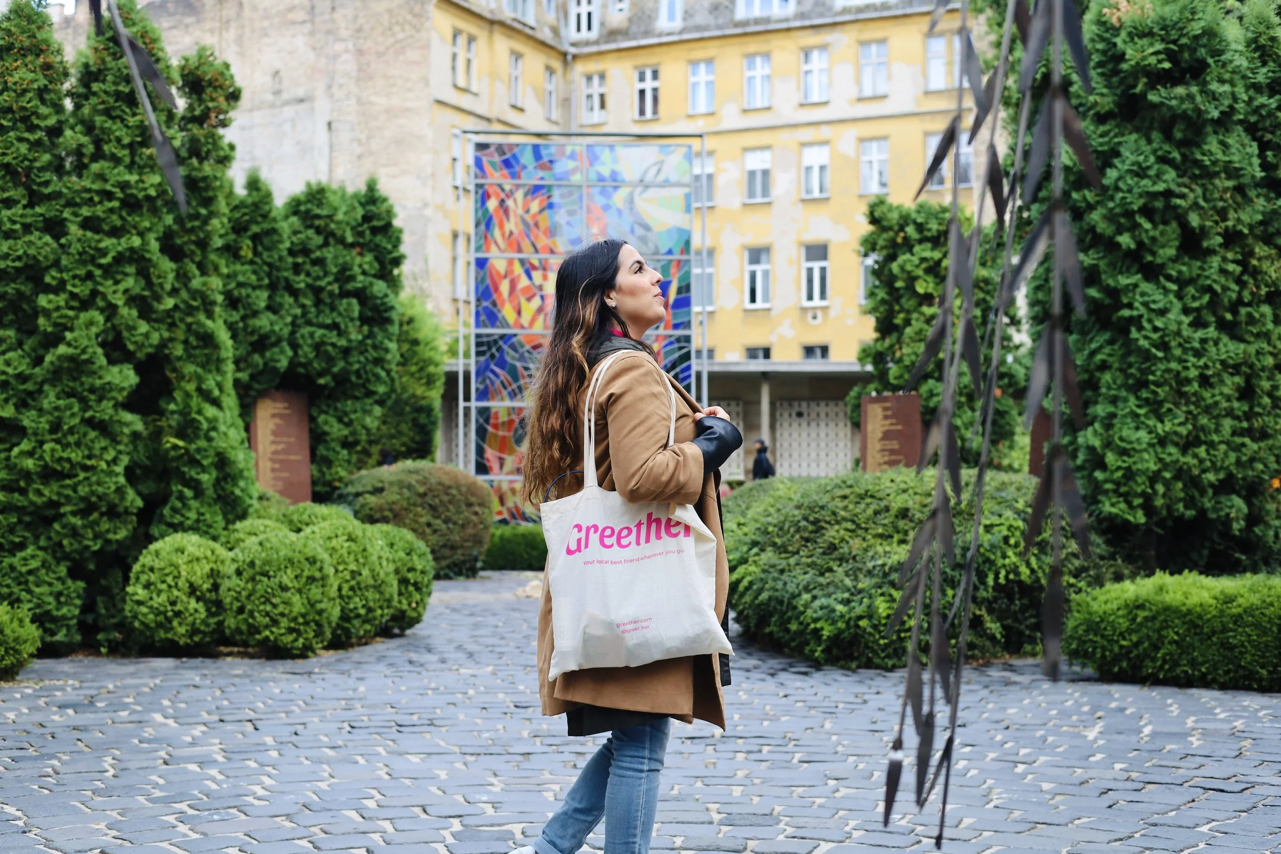 Female traveler exploring a city with a Greether tote bag, showcasing empowered and safe solo travel experiences for women through local female guides